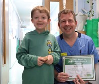 Nurse holding his award certificate standing next to the child who nominated him